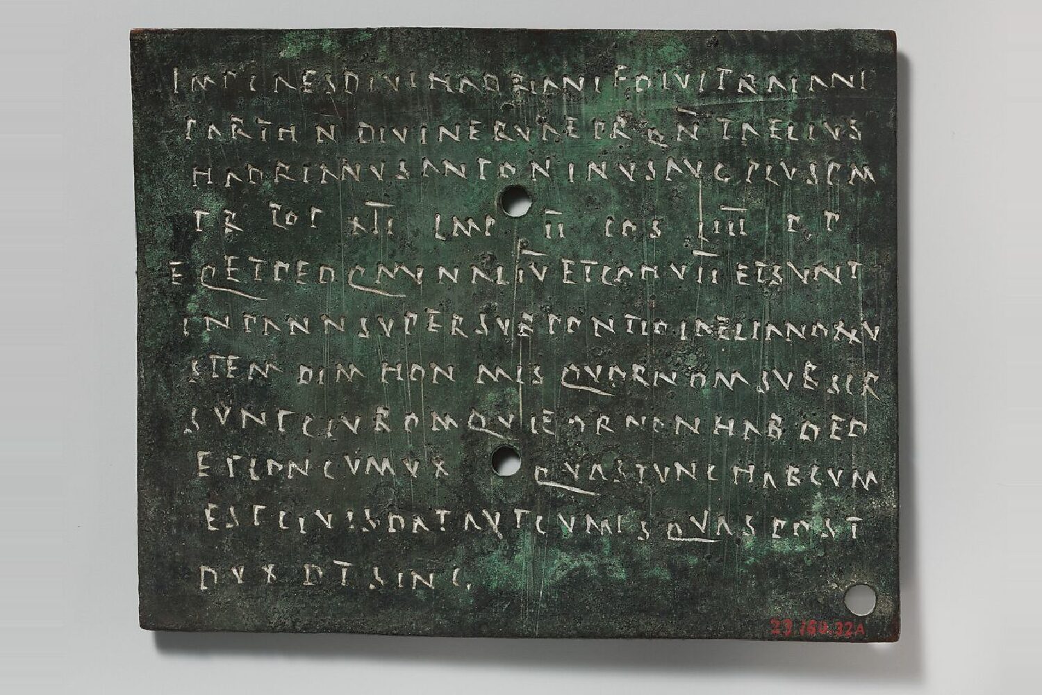 An ancient Roman tablet engraved with lines of Latin capitals, pierced by two binding holes